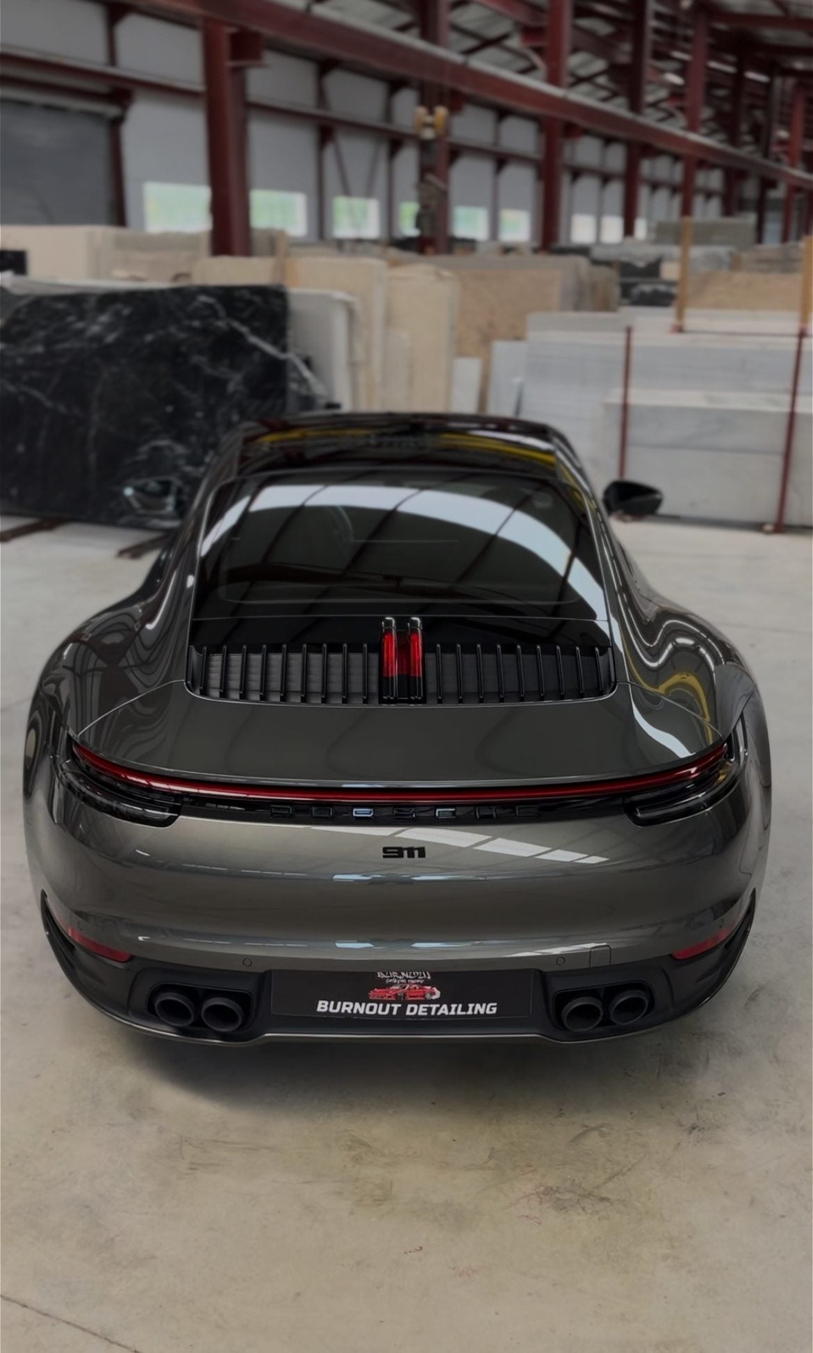 Porsche 911 gris terminado, visto desde atrás, con la placa de Burnout Detailing