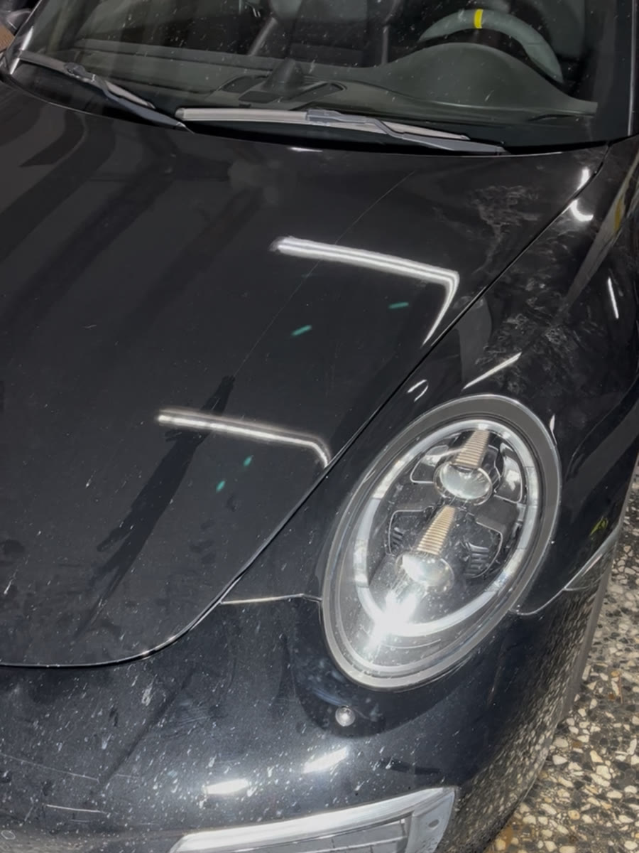 Porsche 911 negro antes del Signature Detail, con polvo y suciedad sobre el capó