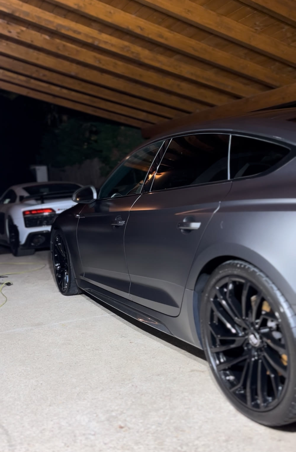 Audi RS 5 recién detallado de noche, junto a un Audi R8, en un servicio a domicilio