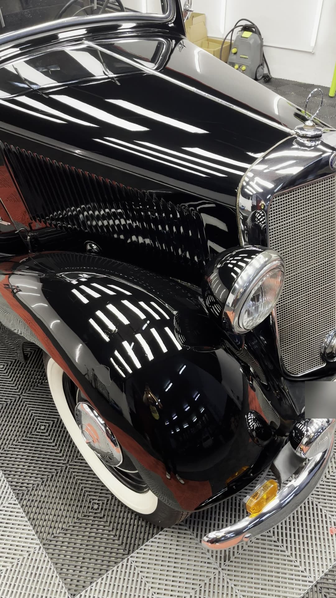 Mercedes clásico negro recién pulido, con los focos reflejados en la aleta como en un espejo