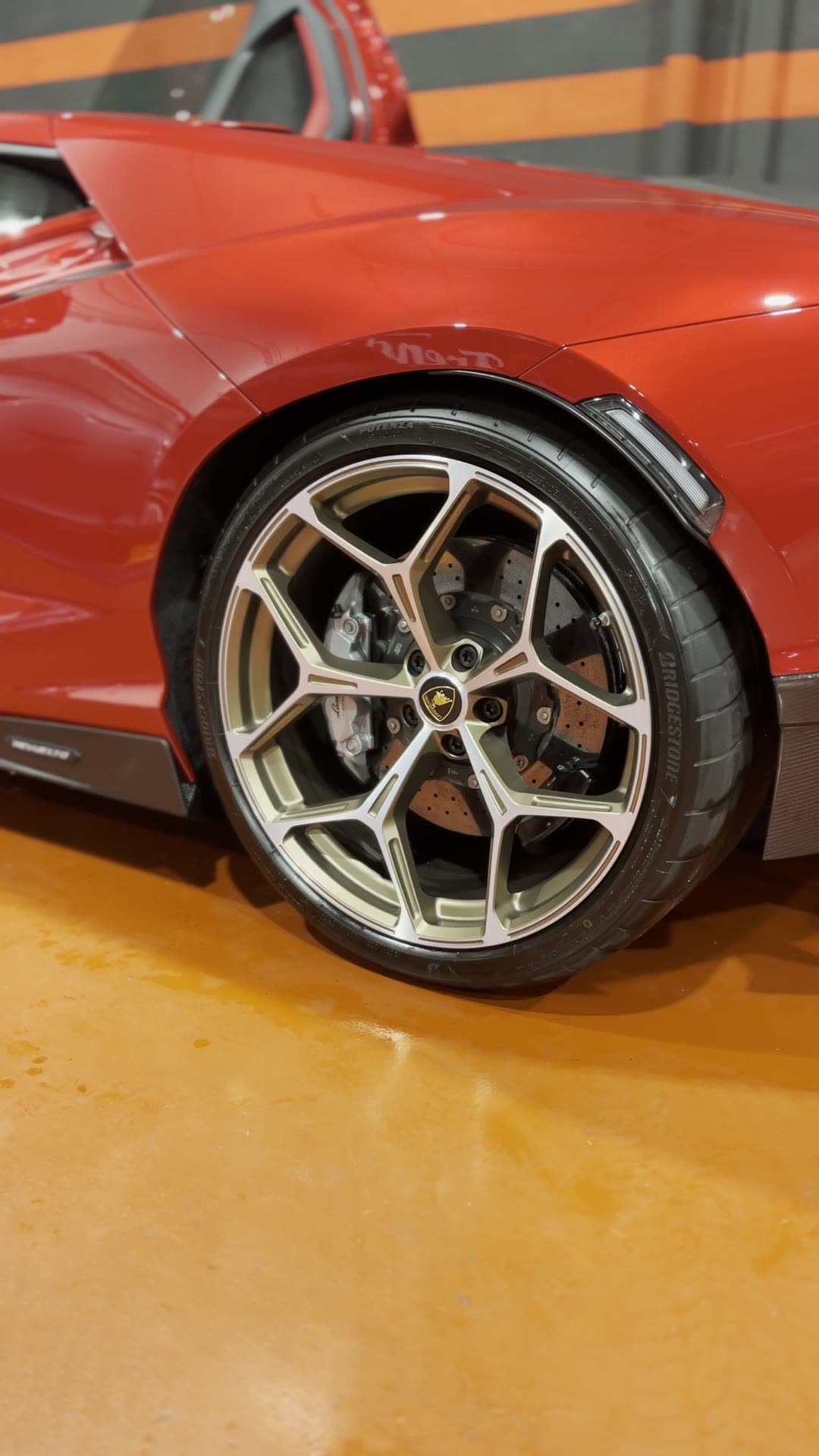 Llanta bronce de un Lamborghini Revuelto rojo, limpia y protegida, con la pinza de freno a la vista